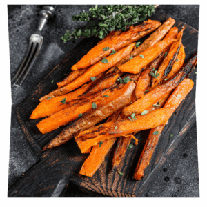 Frites de patates douces sorties du four, parsemées de persil frais, présentées sur une planche de bois.